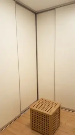 Minimalistisch eingerichteter Raum mit Holzfußboden und hellem Wäschekorb aus Holz.