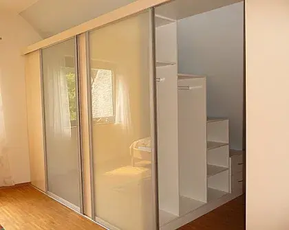 Ein moderner Einbauschrank mit Schiebetüren und offenem Regal in einem Schlafzimmer.