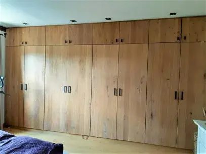 Großer, moderner Einbauschrank aus Holz mit mehreren Türen im Schlafzimmer.