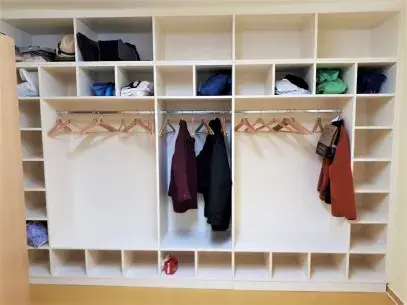 Offener Kleiderschrank aus Holz mit Regalfächern, Kleiderstangen und Kleidung.