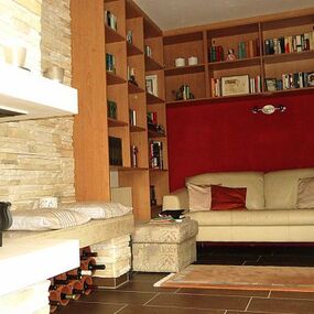 Gemütliches Wohnzimmer mit Kamin, Bücherregal, Sofa und moderner Wohnraumgestaltung.