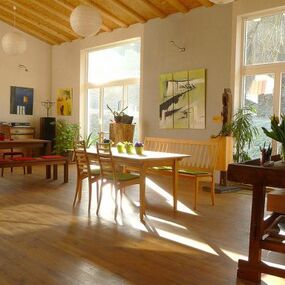 Heller, gemütlicher Essbereich mit Holzmöbeln, Pflanzen und großen Fenstern im modernen Wohnraum.