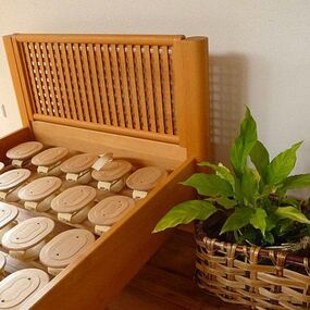 Holzbett mit sichtbarem Lattenrostsystem und geflochtenem Pflanzkorb im Schlafzimmer.