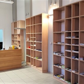 Moderner Empfangsbereich mit Holztheke, Regalen und Infomaterial in einem Büro.